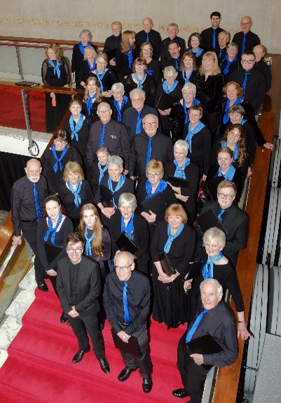 Choir members, in black with blue ties / scarves, on staircase.